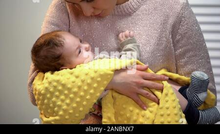 Giovane e bella signora cantando little baby dormire, tenendo accuratamente in armi Foto Stock