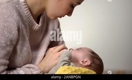 Mom dando poco adorabile kid binky ortodontico, neonato accessori per bambini Foto Stock