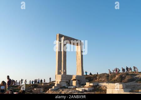 Naxos Grecia - Agosto 12 2019; porta tra i resti del Tempio di Apollo sull isoletta Palatia con i turisti che sono arrivati a vedere il tramonto da questo fa Foto Stock