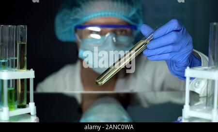 Scienziato analizzando il giallo di estrazione di olio nel tubo per la produzione di prodotti di profumeria Foto Stock