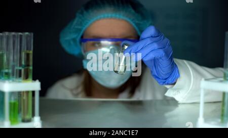 Scienziato tenendo la bottiglia con liquido dal frigo, sviluppo di antibiotico, tossina Foto Stock