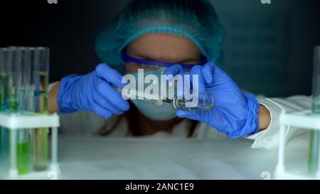 Assistente di laboratorio assunzione del vaccino dal frigo e riempire la siringa epidemie focolaio Foto Stock