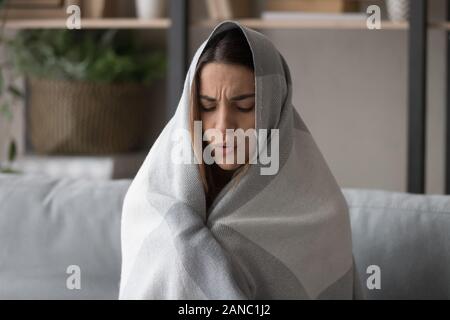 Malsana giovane donna sensazione di freddo, coprendo in plaid. Foto Stock