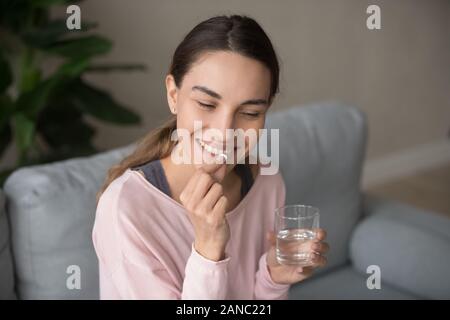 Sorridendo felice donna millenario prendendo quotidianamente vitamine. Foto Stock