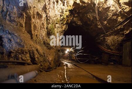 Tunnel con la stazione ferroviaria e la miniera di elettricità cavi dell'attività di estrazione mineraria. La produzione e il concetto di tecnologia. Miniera con ferrovia via - metropolitana Foto Stock