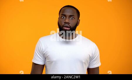 Scioccato afro-americano di uomo che guarda in telecamera isolata su sfondo giallo Foto Stock
