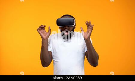 Spaventata afro-americano di uomo con la realtà virtuale auricolare, simulazione, close-up Foto Stock