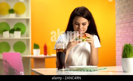 Sorridente brunette lady holding deliziosi burger, un ristorante fast food, tentazione Foto Stock