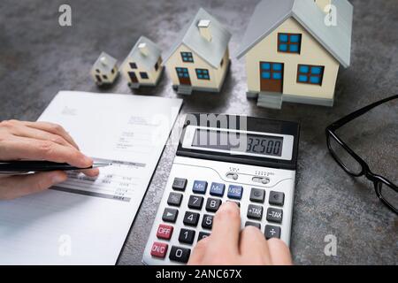 Imprenditore il calcolo fiscale da parte di piccoli e grandi modelli della casa Foto Stock