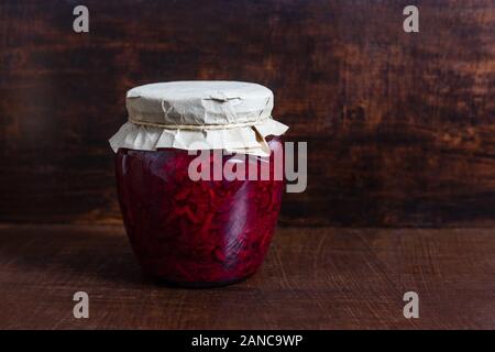 Crauti fatti in casa. Alimento fermentato. Insalata di cavolo con bietole in un vasetto di vetro su di un legno scuro dello sfondo. Copia dello spazio. Foto Stock