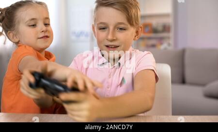 Bambina inquietante fratello la riproduzione di gioco per console, bambini che combattono il joystick Foto Stock