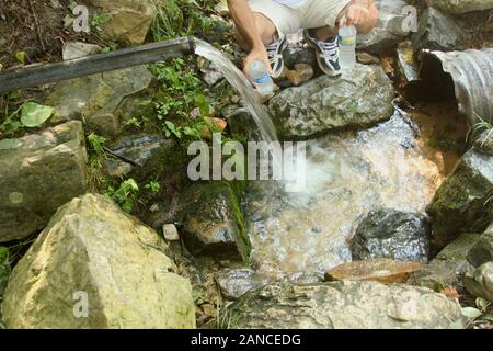 L'uomo il riempimento di bottiglie di acqua dalla cassetta di sicurezza fonte naturale di acqua tra le Blue Ridge Mountains, VA, Stati Uniti d'America Foto Stock