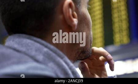 Uomo che guarda un grande schermo di scommesse sportive, la dipendenza dal gioco d'azzardo, close up Foto Stock