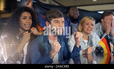 Ansiosi appassionati di calcio con bandiera tedesca di supporto team nazionale in campionato Foto Stock