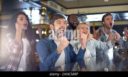 Estremamente felici i fan dello sport attivamente il tifo team, celebrando la vittoria in bar Foto Stock