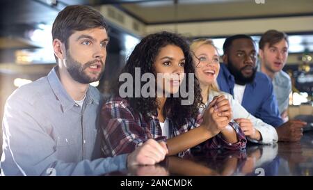 Concentrati gli amici a guardare lo sport la concorrenza nel bar, sperando per la vittoria del team Foto Stock