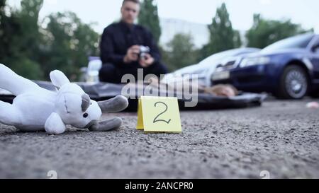 Esperto forense facendo delle foto contrassegnate vittima e testimonianze, giocattolo su strada Foto Stock