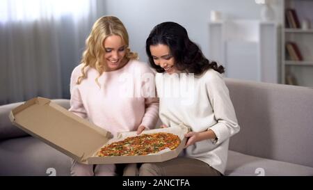 Due sorridente amici di sesso femminile avente la pizza sul lancio di cibo, servizio di consegna Foto Stock