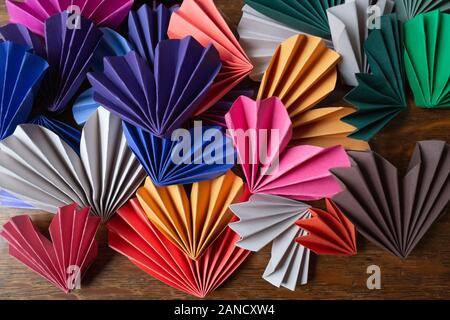 Cuori di carta di origami multicolore su tavola di legno per San Valentino Foto Stock