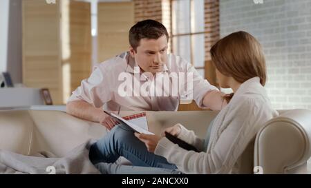 Uomo che guarda moglie rabbiosamente, giovane sostenendo, relazione crisi in famiglia giovane Foto Stock