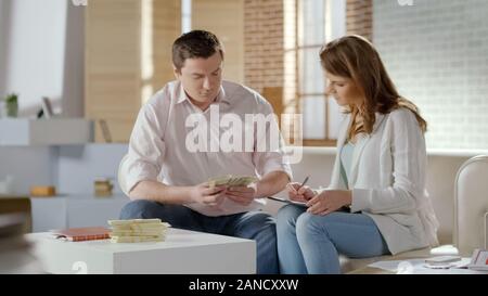 Ricca coppia giovane conteggiare denaro, fornendo alle aziende insieme, bilancio familiare Foto Stock