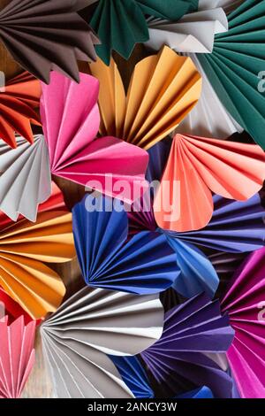 Primo piano di carta multicolore origami cuori stratificati su legno Foto Stock