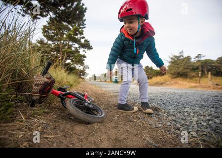 Il bambino si appoggia per prendere la bicicletta. Foto Stock