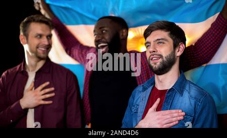 Gioioso ventole argentine il tifo per la squadra di calcio, cantando l'inno sventola bandiera Foto Stock