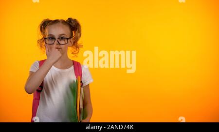 Adorabile ragazza in bicchieri pronti per la scuola, tenendo i notebook e borsa, istruzione Foto Stock