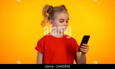 Carina ragazza con smartphone e lettura delle news, comunicando in rete sociale Foto Stock