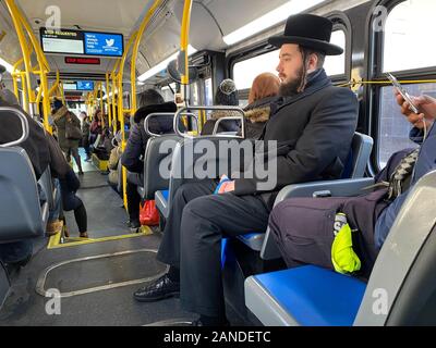 Ebrea ortodossa uomo cavalca un bus locale nella Borough Park quartiere, noto per la sua ortodossa comunità ebraica di Brooklyn, New York. Foto Stock