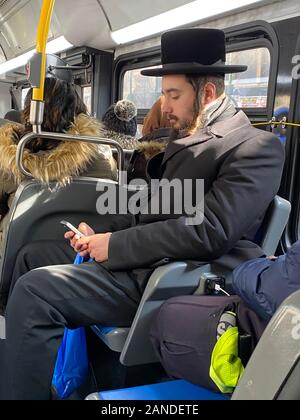 Ebrea ortodossa uomo cavalca un bus locale nella Borough Park quartiere, noto per la sua ortodossa comunità ebraica di Brooklyn, New York. Foto Stock