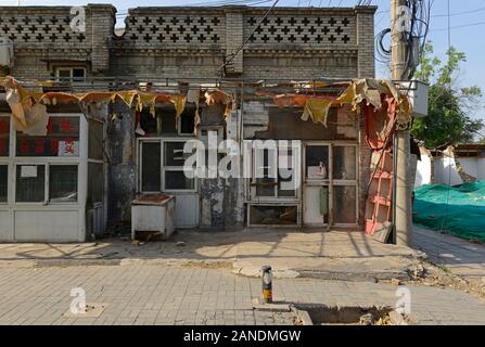 Parzialmente completata demolizione di alcuni piccoli negozi in un hutong residenziale area nel sud di Pechino. Il netting riduce le polveri in sospensione. Pechino, Cina Foto Stock