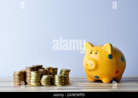Close up Piggybank e monete d'oro sul tavolo Foto Stock