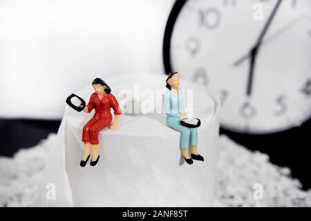 Foto astratte concetto di seduta con un telefono sulla tazza di gabinetto. Foto Stock
