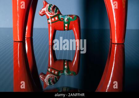 Due fatti a mano in legno tradizionali Dalecarlian cavalli su una superficie riflettente Foto Stock