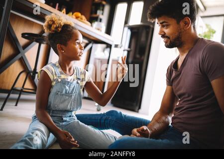 Carino ragazza africana e il suo bello padre sta parlando e sorridente a casa Foto Stock