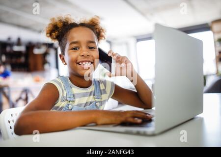 Gioco, studio, concetto di divertimento. Dei bambini felici di trascorrere del tempo con i notebook e tecnologia moderna. Foto Stock