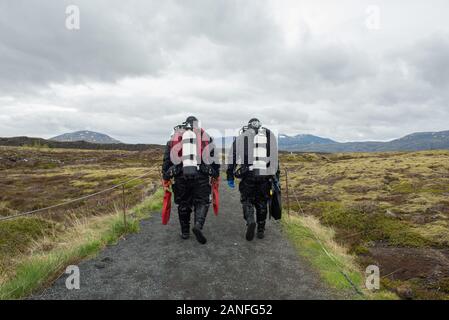 SILFRA, Islanda - 20 Maggio 2019: subacquei camminando su un percorso dopo una immersione Silfra rift, il luogo dove Eurasian e l'Americano targa tettonica Foto Stock