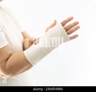 Donna anziana con un supporto polso su sfondo bianco. Donna con dolore al polso Foto Stock