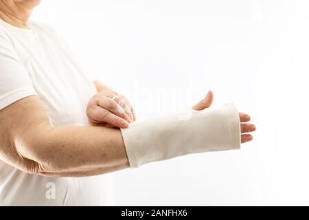 Donna che indossa un bendaggio supporto polso su sfondo bianco. Donna anziana mettendo su un supporto polso Foto Stock