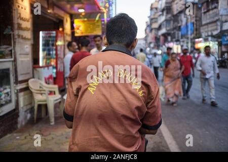 Un uomo di consegna del ristorante indiano del sud Anand Bhuvan in Kalbadevi Road, Bhuleshwar, Mumbai, India, seduto fuori del ristorante Foto Stock