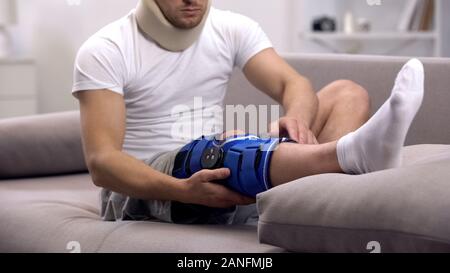 Uomo ferito in schiuma collare cervicale in neoprene di controllo ortesi per ginocchio, riabilitazione Foto Stock