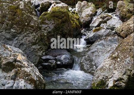 Un fiume cascate giù sopra rocce, tra massi, Foto Stock