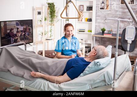 Medico donna con la condivisione di uno stetoscopio comfort al vecchio in casa di cura. Foto Stock