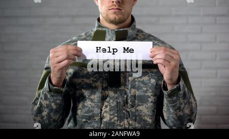 Help me parola scritta sul segno nelle mani del soldato maschio, assistenza medica Foto Stock