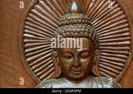 In prossimità di uno in legno intagliato testa di Buddha con un aura mistica intorno alla sua testa. Situato presso il nepalese Pagoda della Pace a Brisbane, South Bank Parklands Foto Stock