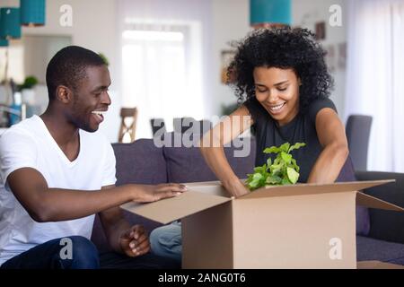 Nero eccitato giovane disimballaggio scatole in movimento insieme Foto Stock