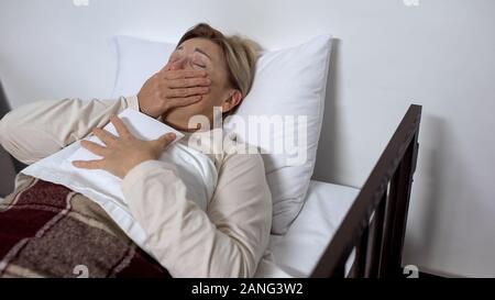 Il pianto malata abbracciando foto di famiglia, giacenti nel letto di ospedale, memorie preziose Foto Stock