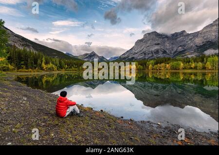 L'uomo viaggiatore rilassante in stagno a cuneo al mattino a Kananaskis country, Canada Foto Stock